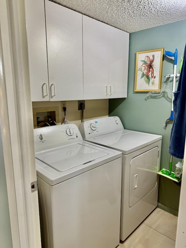 laundry room featuring separate washer and dryer, light tile patterned floors, cabinets, and a textured ceiling