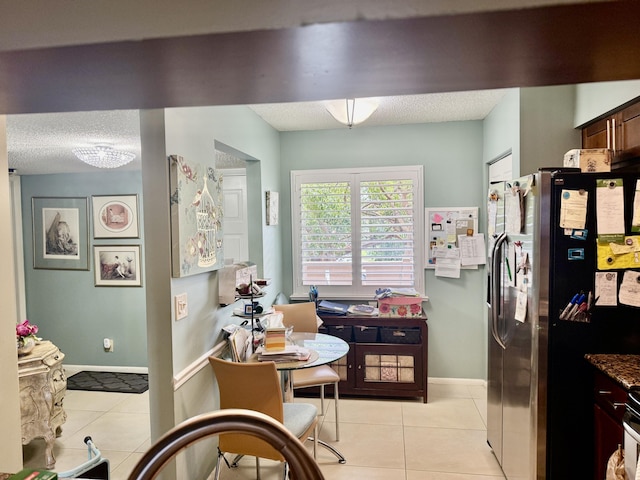 kitchen with light tile patterned flooring, dark brown cabinetry, stainless steel fridge with ice dispenser, and a textured ceiling