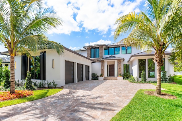 3100 Palm Dr, Delray Beach, FL 33483 - view of front of house with stucco siding, an attached garage, a standing seam roof, decorative driveway, and metal roof
