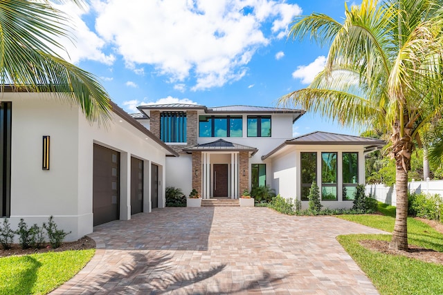 3100 Palm Dr, Delray Beach, FL 33483 - view of front facade with decorative driveway, an attached garage, metal roof, stucco siding, and a standing seam roof