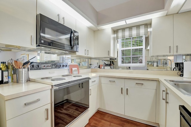 kitchen with electric range, sink, white cabinetry, and dark hardwood / wood-style floors