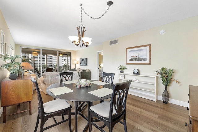 dining space with hardwood / wood-style flooring and a notable chandelier