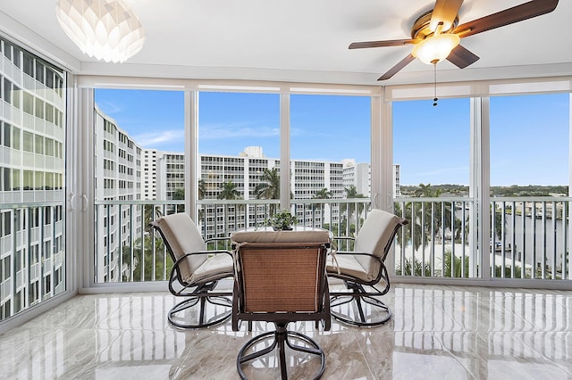 sunroom featuring a water view, a wealth of natural light, and ceiling fan