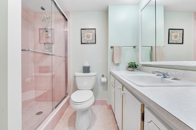 bathroom featuring toilet, vanity, tile patterned floors, and a shower with shower door