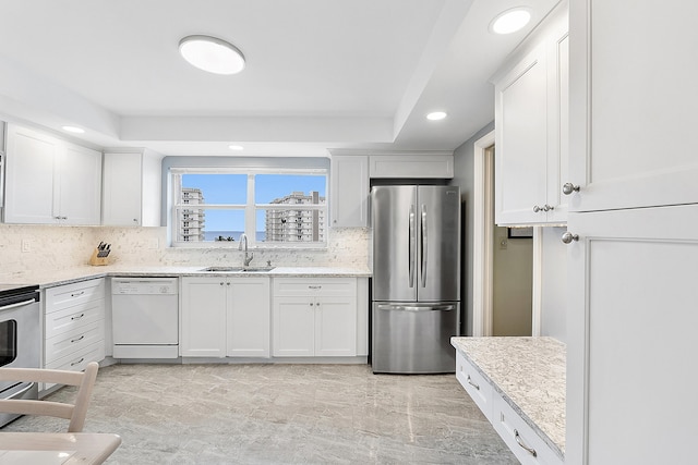 kitchen featuring tasteful backsplash, sink, white cabinets, light stone counters, and stainless steel appliances