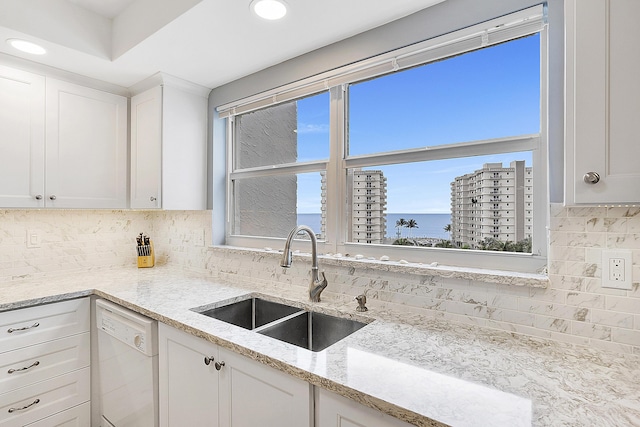 kitchen with sink, white cabinetry, a water view, white dishwasher, and tasteful backsplash