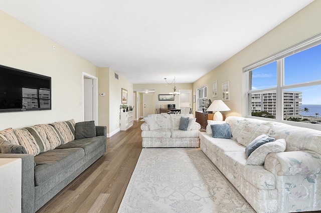 living room with wood-type flooring, a water view, and a notable chandelier