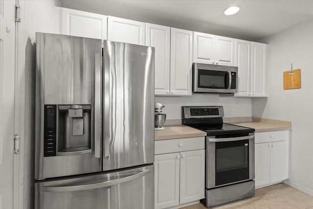 kitchen with white cabinets, light tile patterned floors, stainless steel appliances, and light countertops