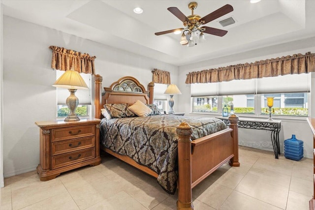 bedroom with multiple windows, ceiling fan, and a tray ceiling