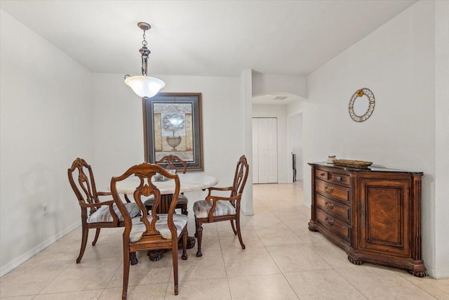 dining space featuring arched walkways, baseboards, and light tile patterned floors