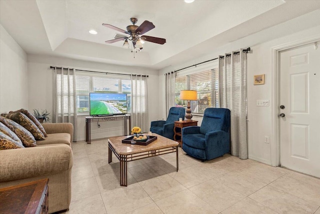 living room with ceiling fan, light tile patterned floors, and a tray ceiling