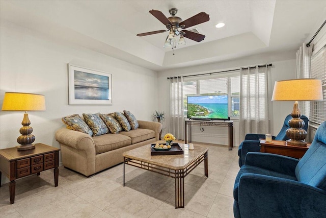 living room with ceiling fan, a tray ceiling, light tile patterned floors, and recessed lighting