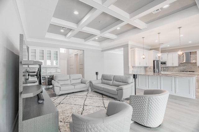 living room with beamed ceiling, wine cooler, light hardwood / wood-style floors, crown molding, and coffered ceiling