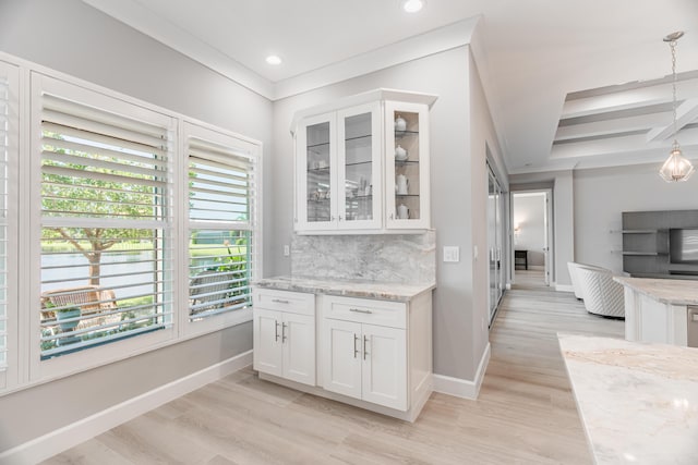 kitchen with pendant lighting, white cabinets, tasteful backsplash, light wood-type flooring, and light stone counters