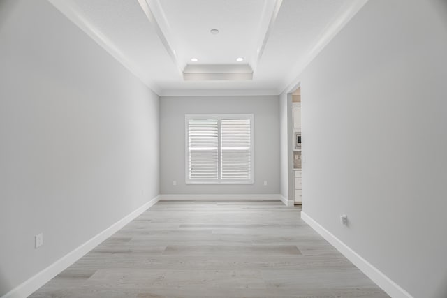 hall featuring ornamental molding, a raised ceiling, and light hardwood / wood-style flooring