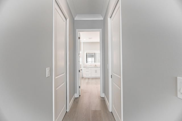 hall with light hardwood / wood-style floors and crown molding