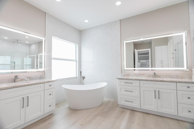 bathroom with independent shower and bath, wood-type flooring, and vanity