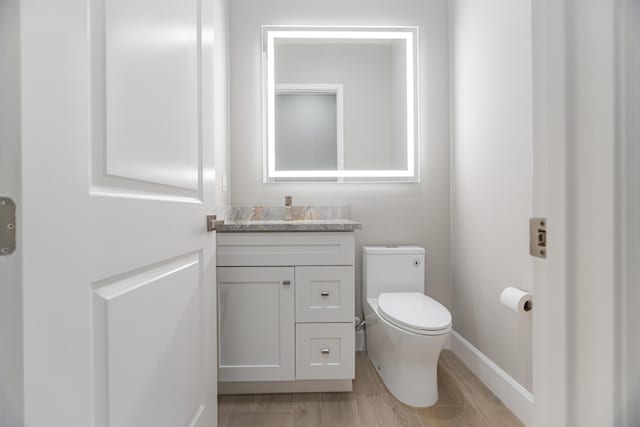 bathroom with toilet, vanity, and hardwood / wood-style flooring