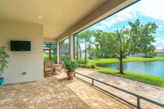 view of patio featuring glass enclosure and a water view