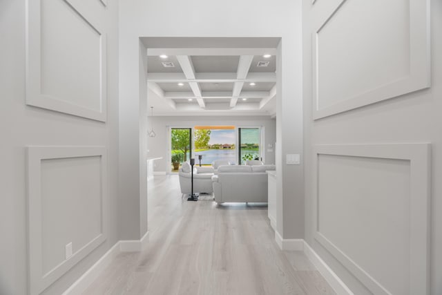 hall with light hardwood / wood-style flooring, beamed ceiling, and coffered ceiling