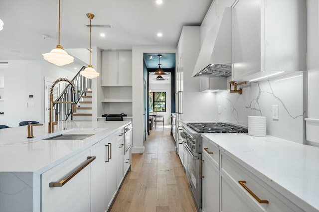 kitchen featuring light wood-type flooring, premium range hood, pendant lighting, white cabinets, and high end stainless steel range