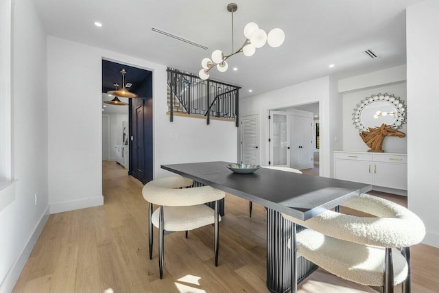 dining area featuring light wood-type flooring and a notable chandelier