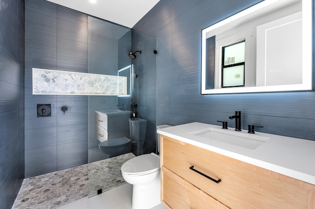 bathroom featuring toilet, vanity, tile patterned floors, and tiled shower