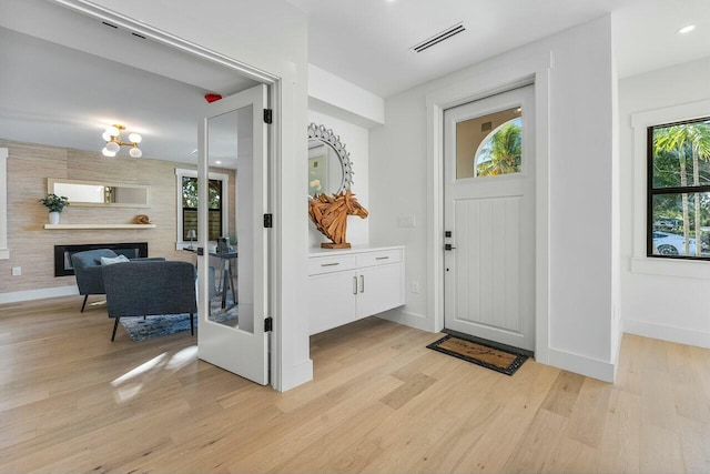 entrance foyer featuring a large fireplace, light wood-type flooring, and french doors