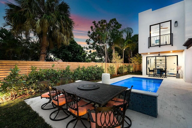 pool at dusk featuring a patio