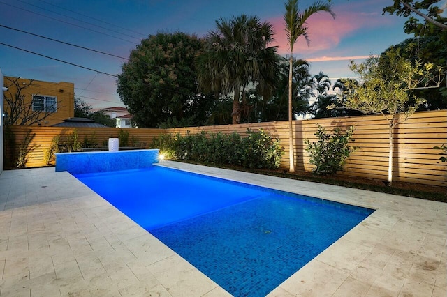 pool at dusk featuring a patio