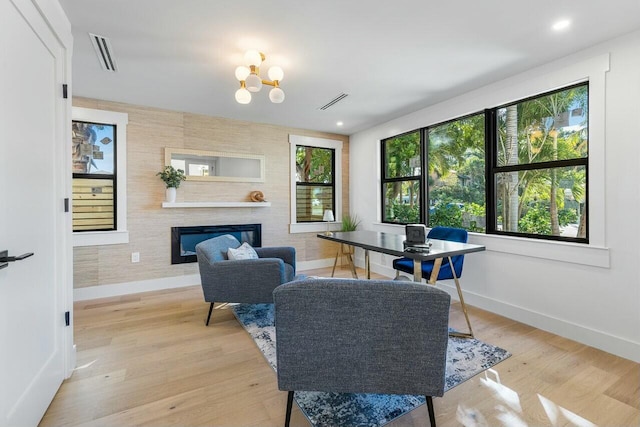 dining area featuring a fireplace, light wood-type flooring, and an inviting chandelier