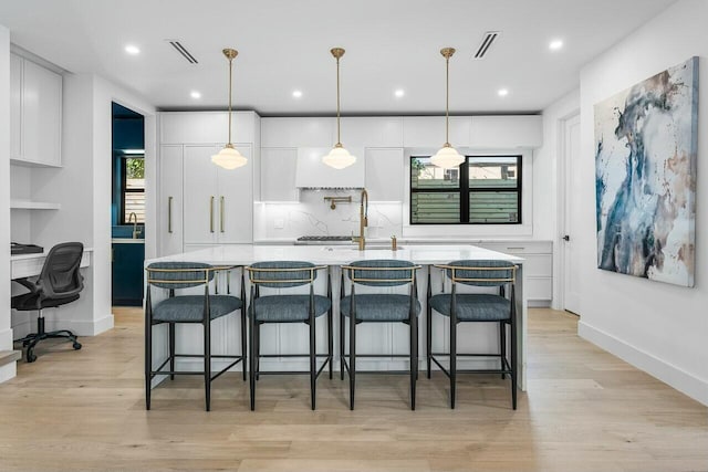 kitchen with white cabinets, a breakfast bar area, and a center island with sink