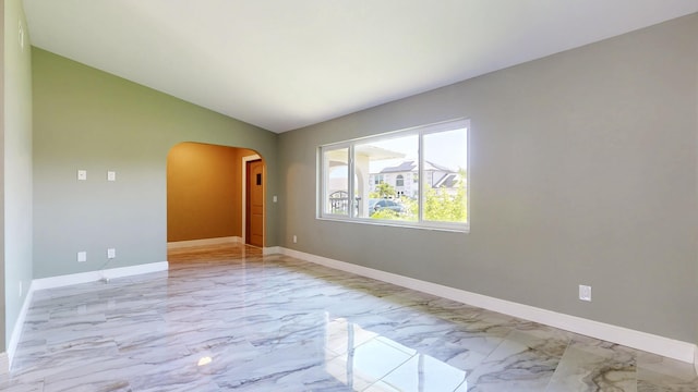 601 SE Karrigan Ter, Port Saint Lucie, FL 34983 - unfurnished room featuring arched walkways, light marble finish flooring, and vaulted ceiling