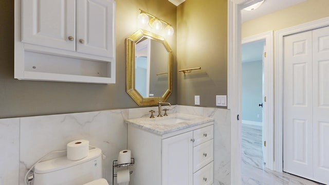 601 SE Karrigan Ter, Port Saint Lucie, FL 34983 - half bath featuring tile walls, marble finish flooring, vanity, and a wainscoted wall