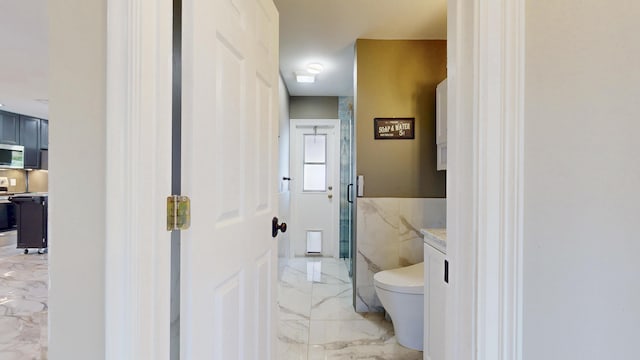 601 SE Karrigan Ter, Port Saint Lucie, FL 34983 - bathroom with marble tiled flooring, tile walls, a marble finish shower, vanity, and wainscoting