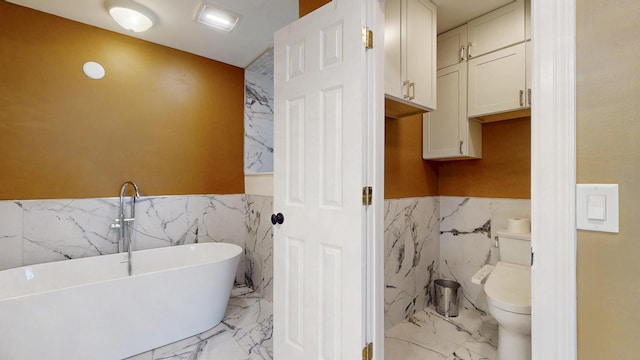 601 SE Karrigan Ter, Port Saint Lucie, FL 34983 - full bath with tile walls, a freestanding bath, a wainscoted wall, and marble tiled floors