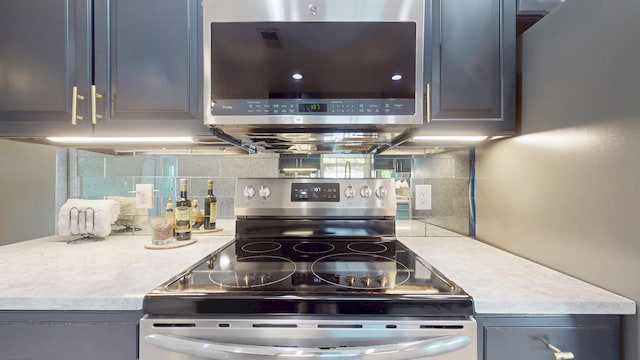 601 SE Karrigan Ter, Port Saint Lucie, FL 34983 - kitchen with water heater, stainless steel electric range, light countertops, decorative backsplash, and gray cabinetry