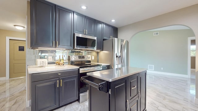601 SE Karrigan Ter, Port Saint Lucie, FL 34983 - kitchen with appliances with stainless steel finishes, arched walkways, light marble finish floors, light countertops, and backsplash