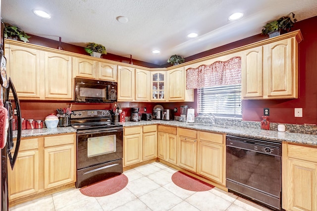 kitchen with sink, light stone counters, a textured ceiling, light brown cabinets, and black appliances