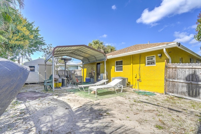 back of property with cooling unit, a carport, and a storage shed