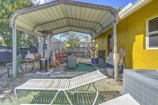 view of patio / terrace with cooling unit, a carport, and a storage unit