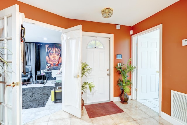 entryway featuring light tile patterned floors and ornate columns