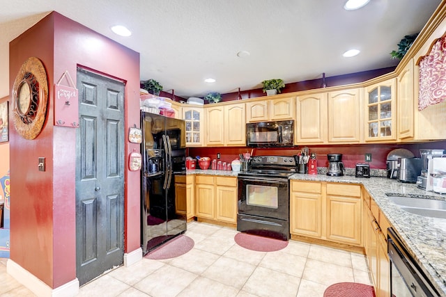 kitchen with sink, light tile patterned floors, black appliances, light stone countertops, and light brown cabinets