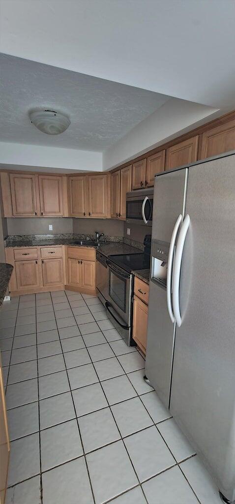 2425 Presidential Way Unit 402, West Palm Beach, FL 33401 - kitchen featuring appliances with stainless steel finishes, dark countertops, and light tile patterned floors