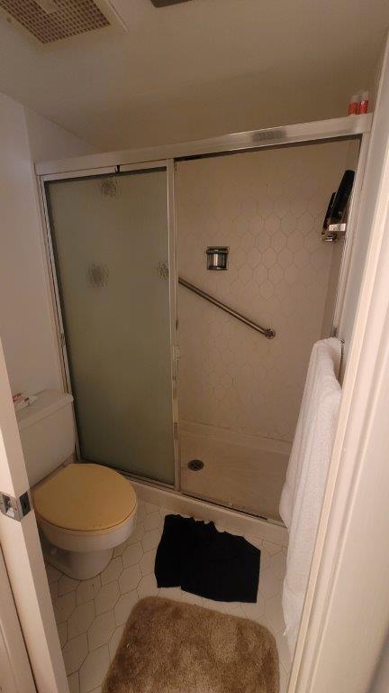 bathroom featuring tile patterned flooring, toilet, and a shower with door