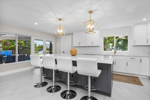 kitchen with a kitchen island, decorative backsplash, pendant lighting, and white cabinetry