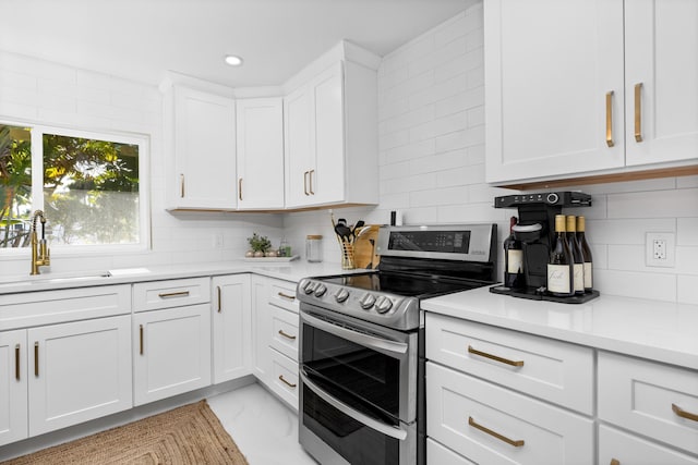 kitchen featuring white cabinets, decorative backsplash, double oven range, and sink