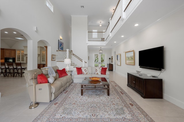 tiled living room featuring crown molding and a towering ceiling