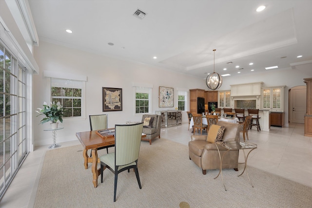 dining room featuring a tray ceiling, light tile patterned floors, and crown molding