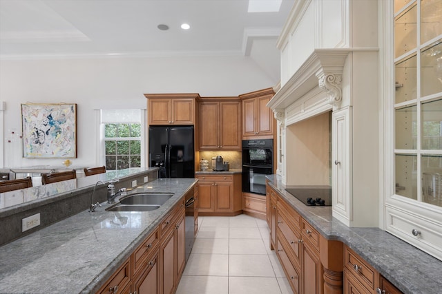 kitchen with sink, dark stone counters, light tile patterned floors, black appliances, and crown molding